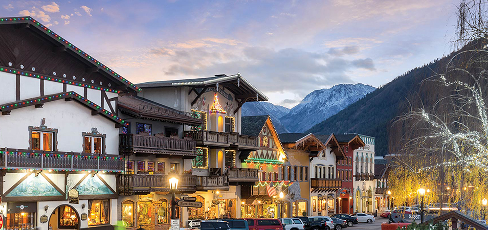 A city street with decorated Bavarian buildings and mountains in the background in Leavenworth, Washington